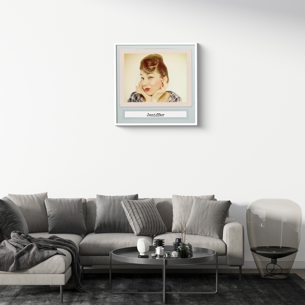 Vintage portretposter met eigen naam in een witte lijst boven een grijze hoekbank in de woonkamer
