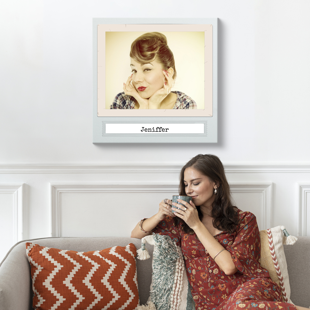 Groot vintage portret met eigen naam aan een witte muur boven een bank met kussens met een patroon