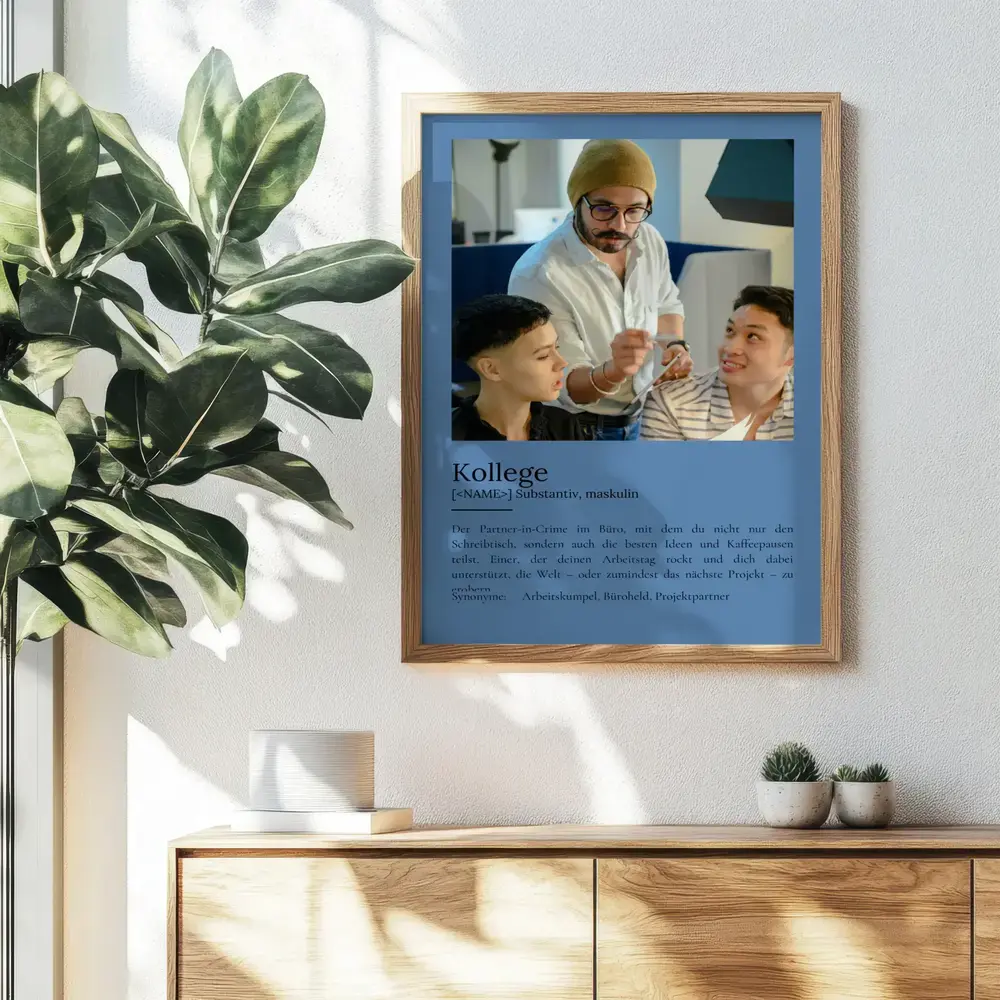Blaues Definitionsposter für Kollegen mit großem Foto im Holzrahmen über einem Sideboard neben einer Pflanze