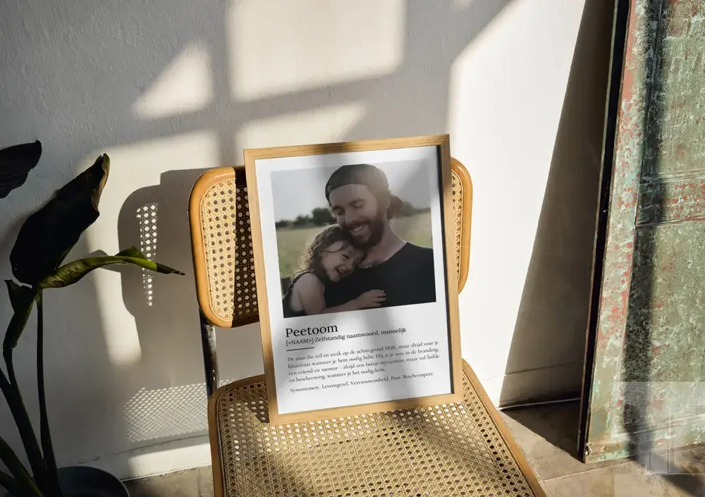 Definitieposter voor peetoom met eigen foto en tekst in een houten lijst, op een stoel met gevlochten zitting