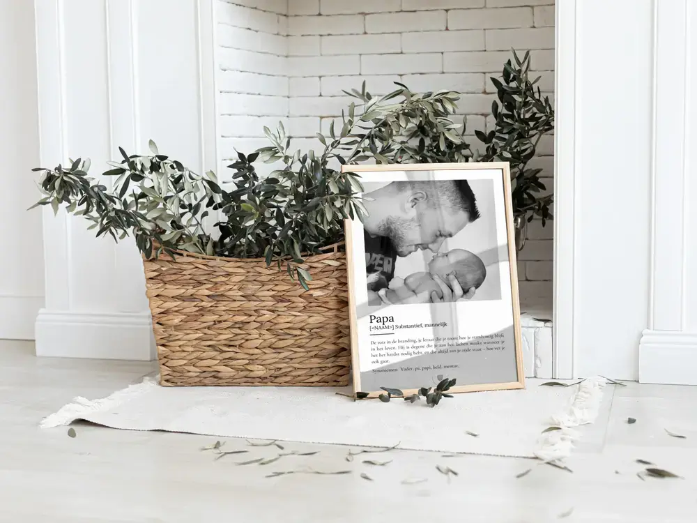 Poster met foto en definitie van papa in een houten lijst, op de vloer naast een gevlochten plantenmand