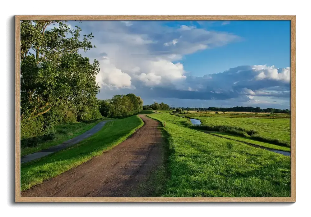 Landschapsfoto op plexiglas met een landweg en groene weiden, in een naturel houten lijst
