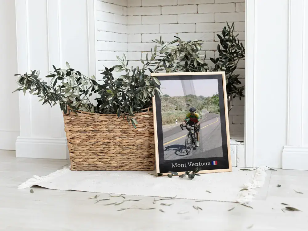 Gerahmtes Rennradfoto mit Ortszeile am Boden neben einem Pflanzenkorb, als Geschenk für Rennradfans