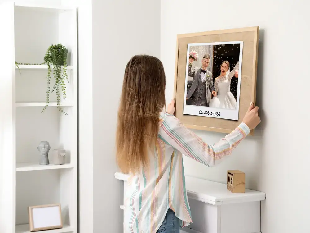Trouwfoto met datum in een lichte houten lijst aan een witte muur, als persoonlijk huwelijkscadeau