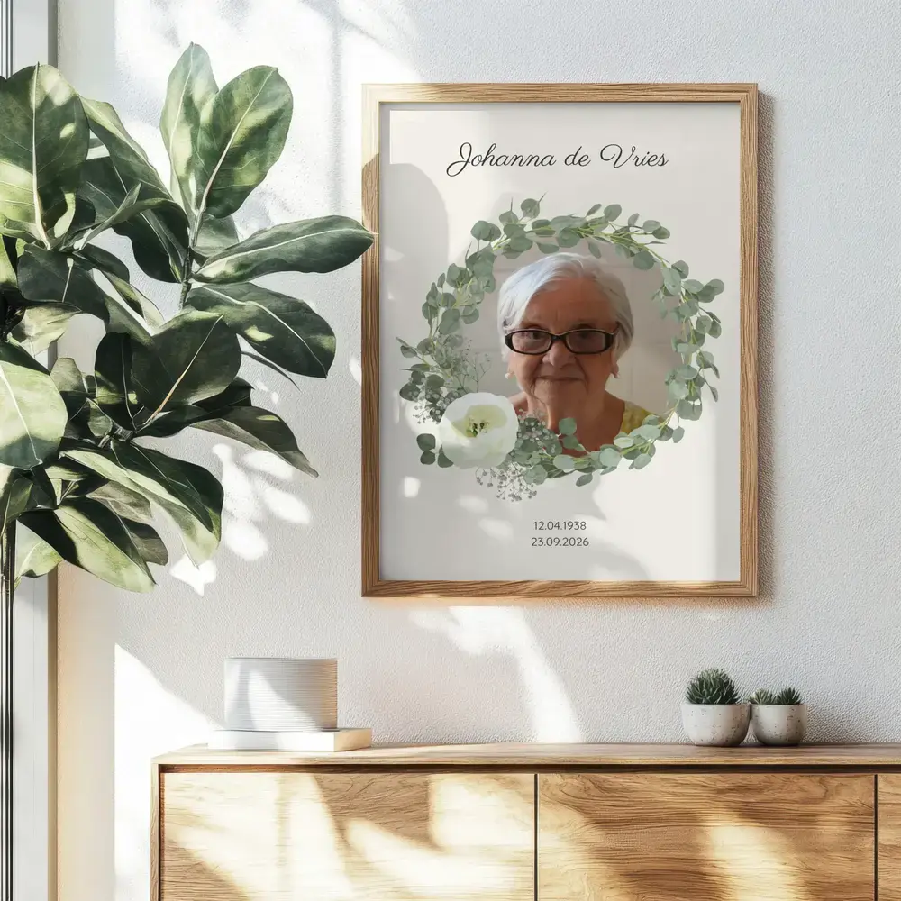 Herdenkingsportret met eucalyptuskrans in een naturel houten lijst, aan de muur boven een dressoir