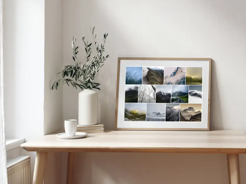 Fotocollage van mistige bergen en bos in een naturel houten lijst op een licht bureau naast een vaas