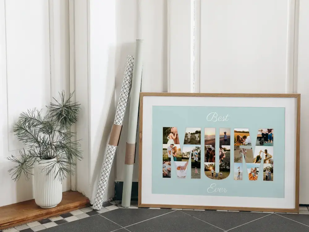 Buchstaben-Fotocollage im Naturholzrahmen am Boden neben einer Pflanze als liebevolle Geschenkidee für Mama