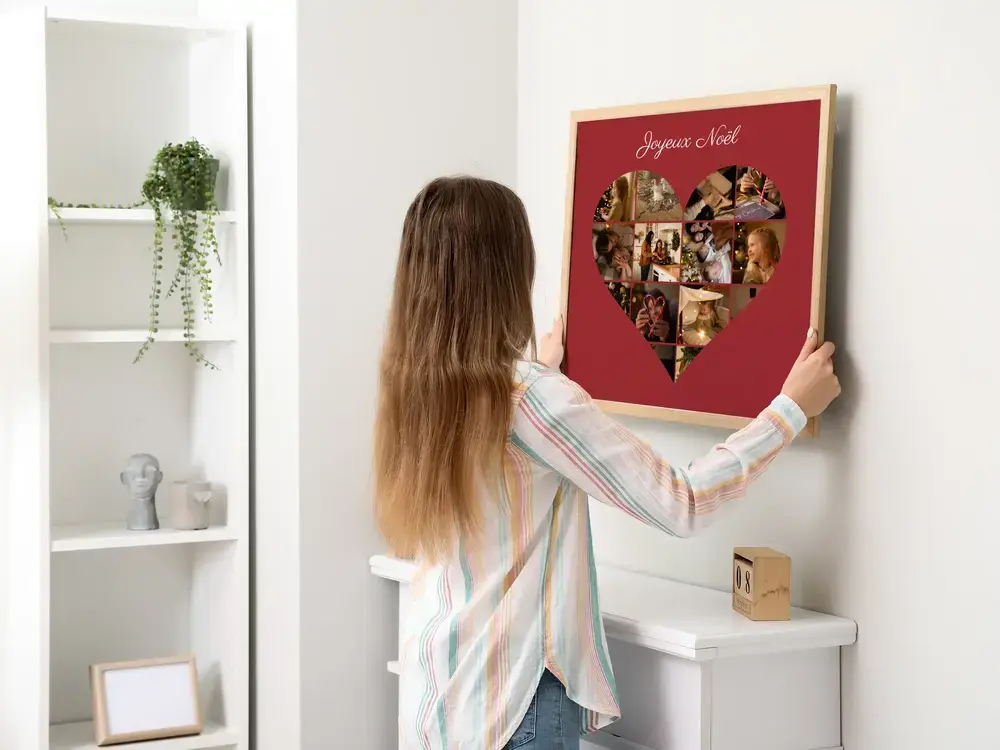 Cadeau de Noël : collage photo en cœur sur fond rouge, encadré en bois clair sur un mur blanc