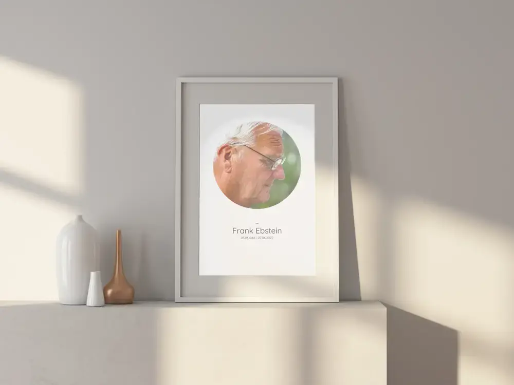 Herdenkingsfoto met rond portret en levensdata in een lichte lijst op een wit dressoir naast vazen