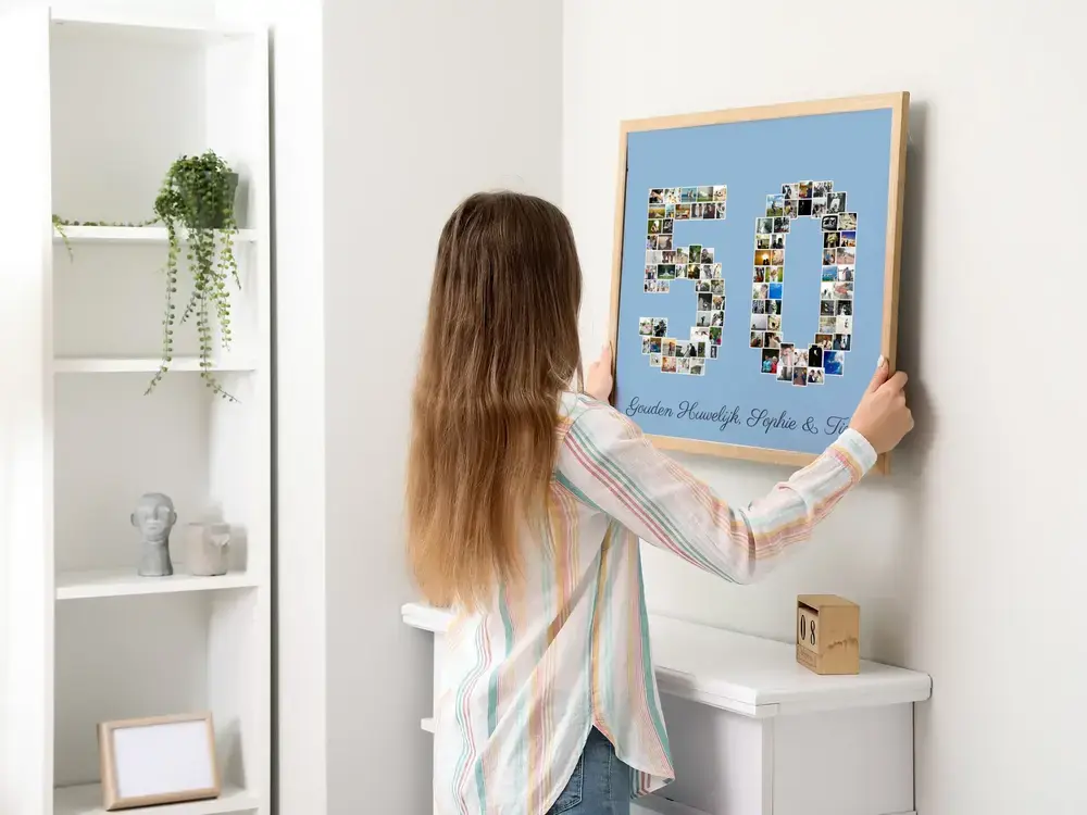 Fotocollage in de vorm van 50 met namen op blauwe achtergrond, in houten lijst boven een witte schouw
