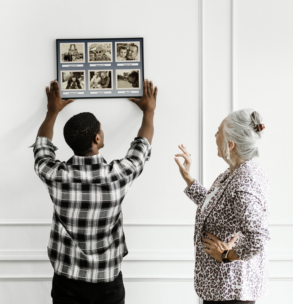 Retro collage van 6 sepia familiefoto’s met datums, in een zwarte lijst tegen een witte wand met sierlijsten
