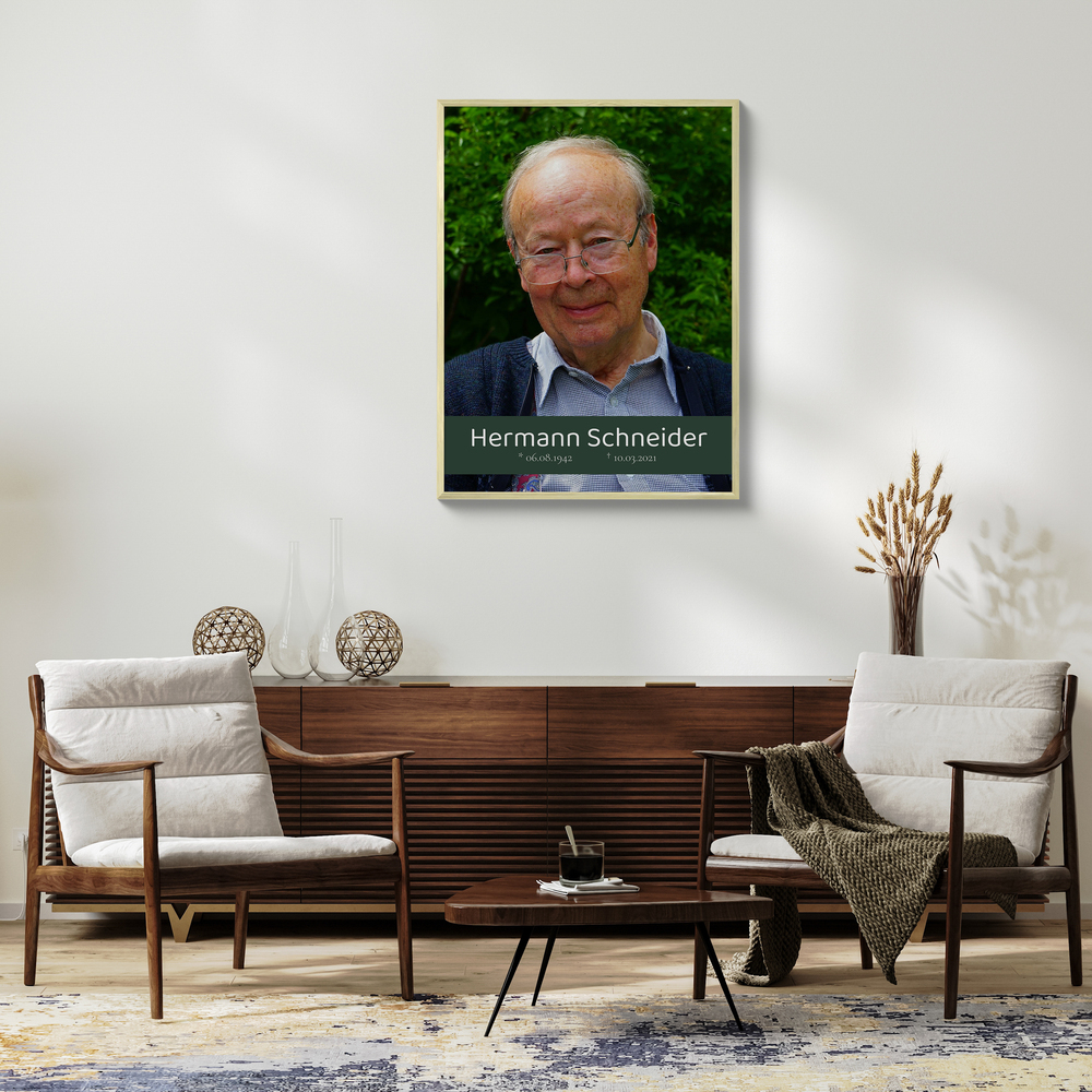 Gerahmtes Trauerporträt mit Namen und Lebensdaten auf grünem Textbanner über einem Sideboard im Wohnzimmer