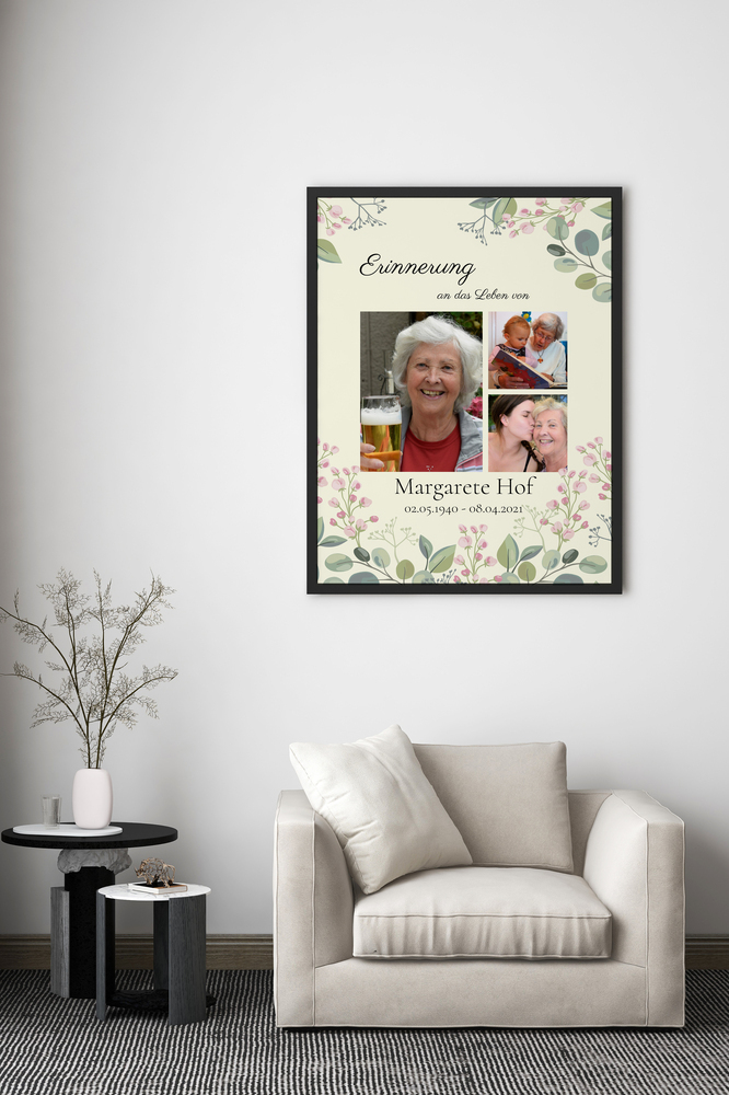 Trauercollage mit drei Fotos und Blumenmotiv im schwarzen Rahmen über einem hellen Sessel im Wohnzimmer